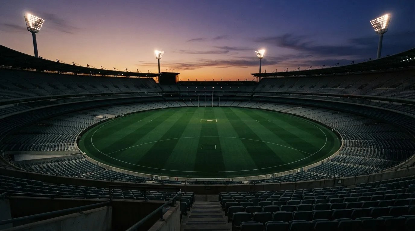 An empty football stadium with floodlight masts at dusk