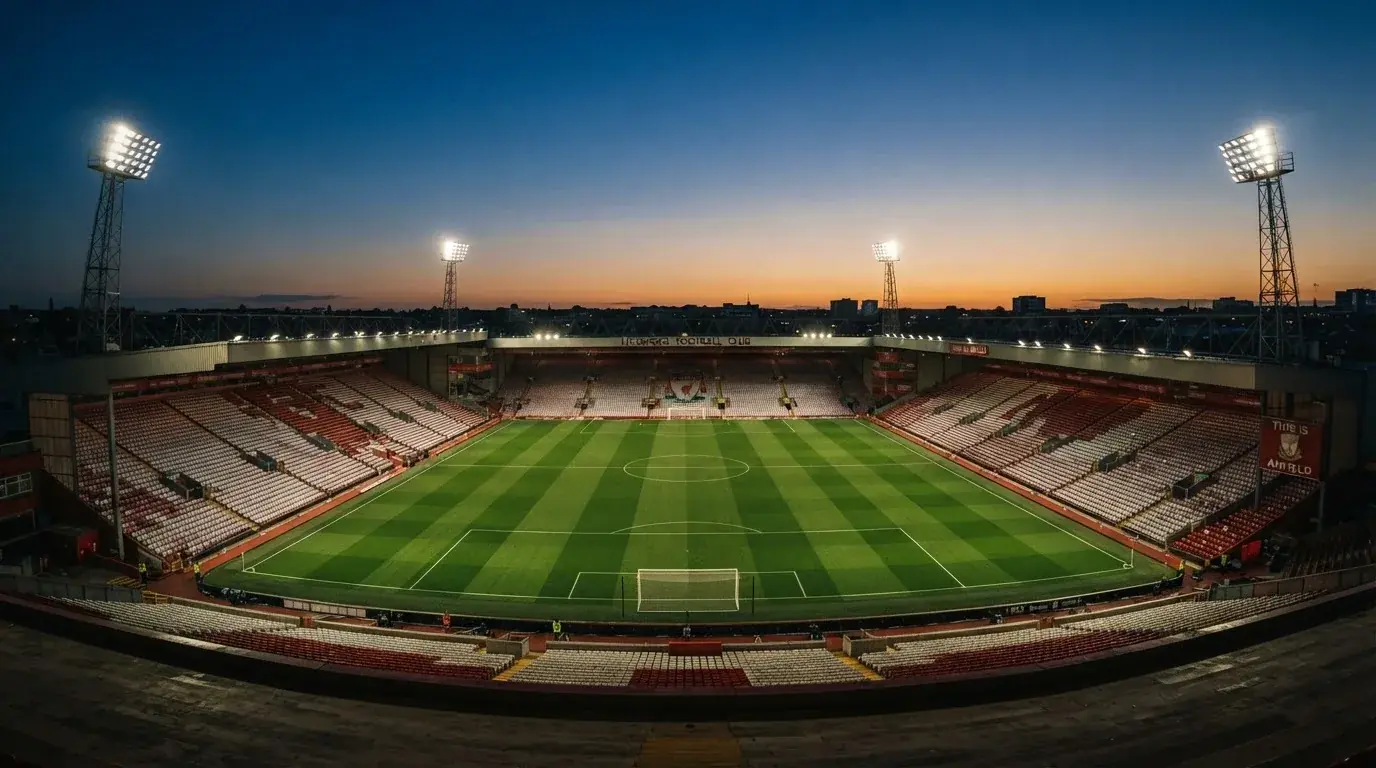 An empty football stadium with floodlight masts at dusk