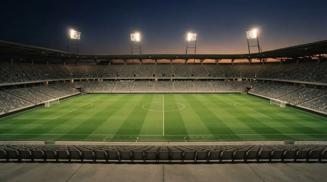 An empty football stadium with floodlight masts at dusk