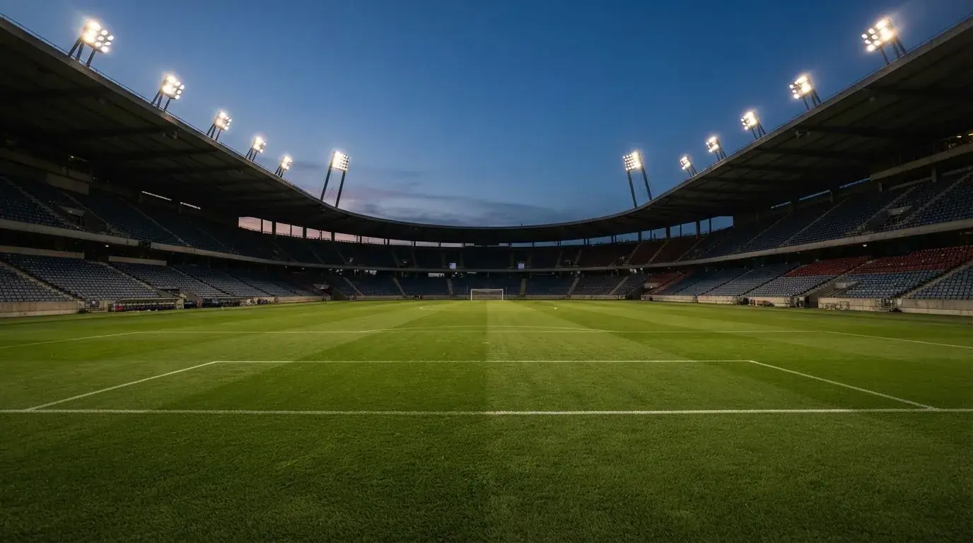 An empty football stadium with floodlight masts at dusk