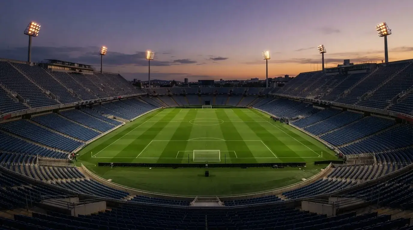 An empty football stadium with floodlight masts at dusk
