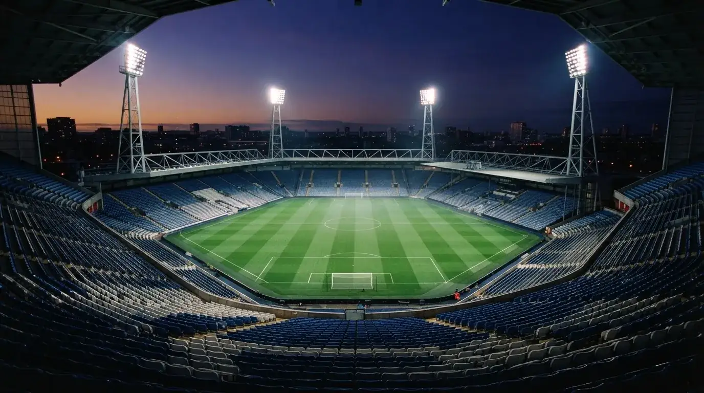 An empty football stadium with floodlight masts at dusk