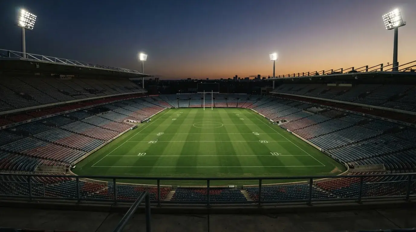 An empty football stadium with floodlight masts at dusk