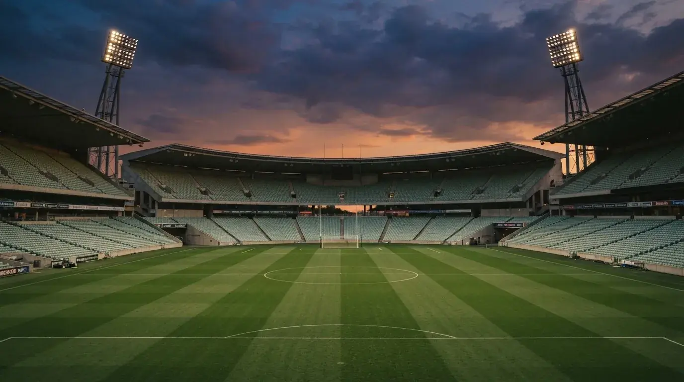 An empty football stadium with floodlight masts at dusk