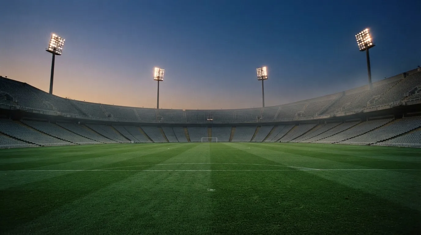 An empty football stadium with floodlight masts at dusk