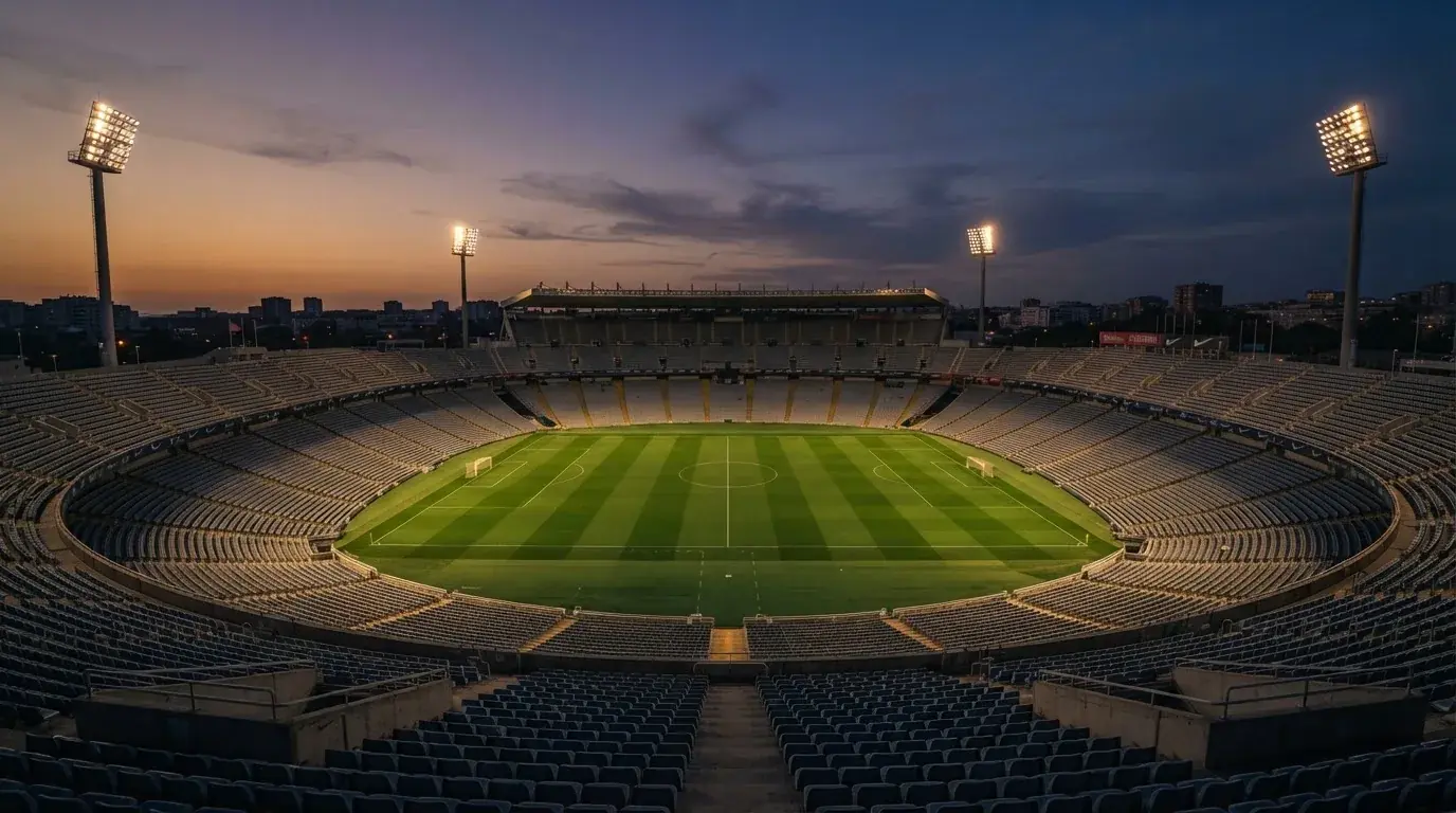 An empty football stadium with floodlight masts at dusk